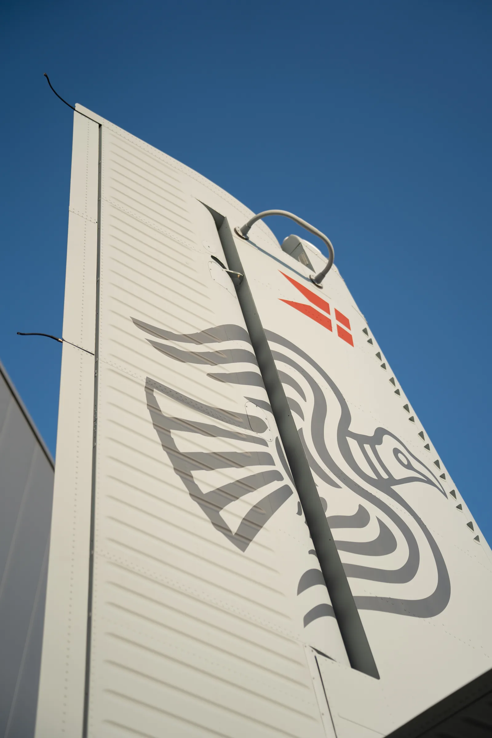 The tail of a Danish Home Guard Twin Otter, painted with a stylised bird, against a deep blue sky