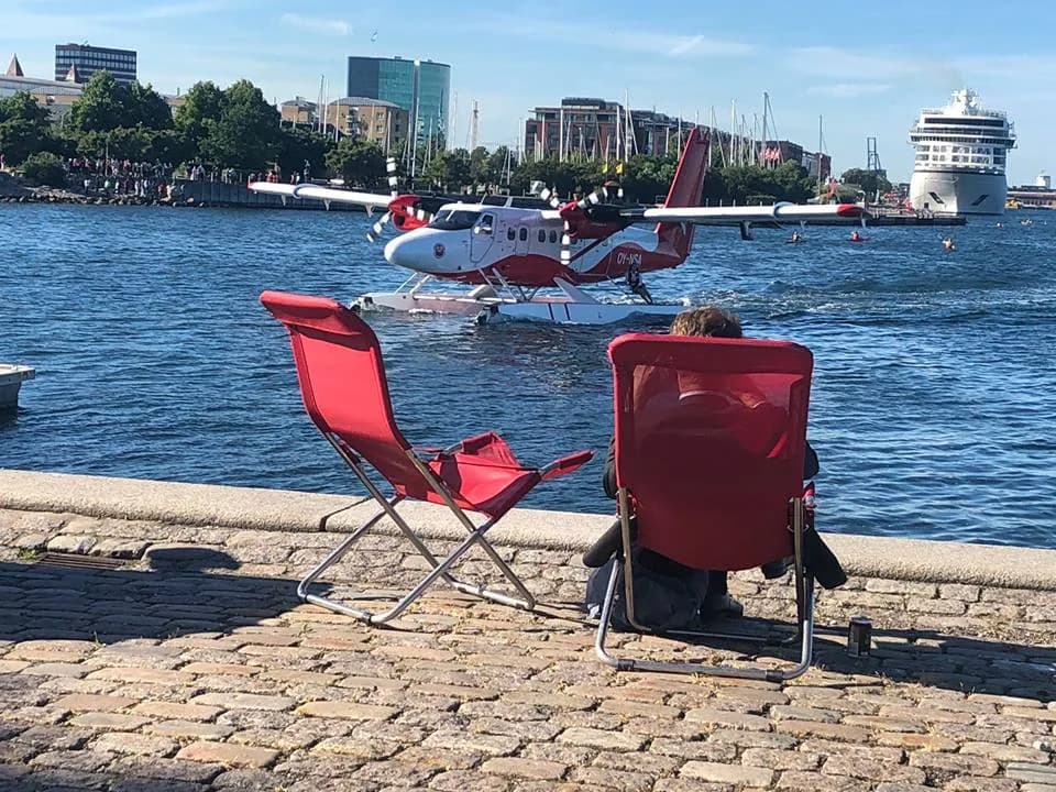Twin Otter on floats in Copenhagen harbour, two red deckchairs on the quay